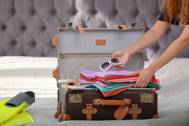 Photo of Woman packing suitcase for journey at home