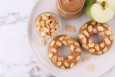 Fresh green apple with peanut butter and nuts on white marble table, top view