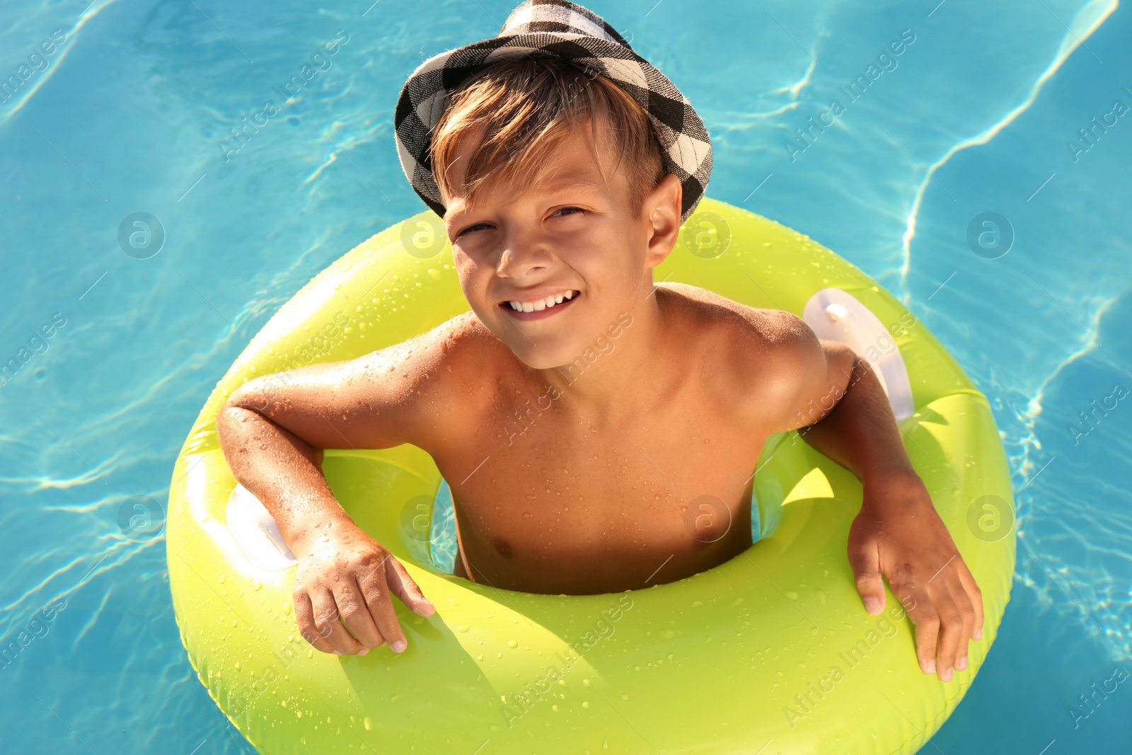 Photo of Happy cute boy with inflatable ring in swimming pool