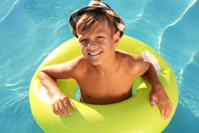 Photo of Happy cute boy with inflatable ring in swimming pool