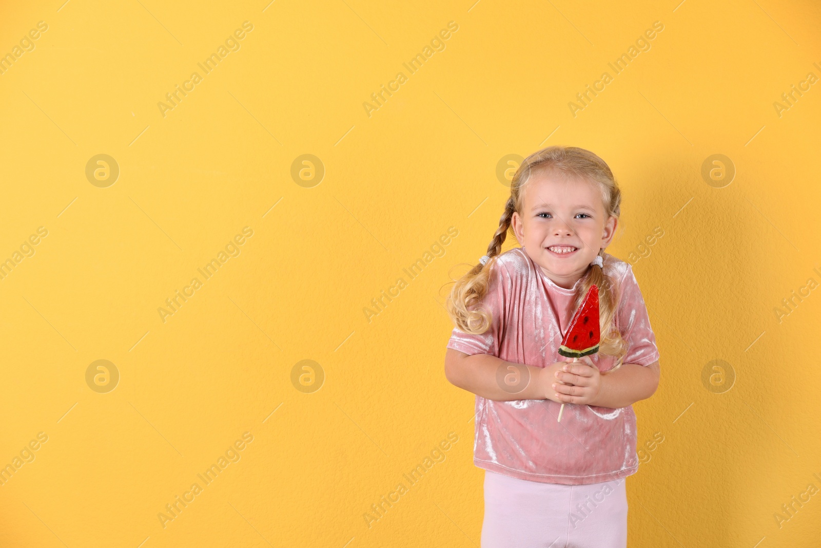 Photo of Cute little girl with candy on color background. Space for text