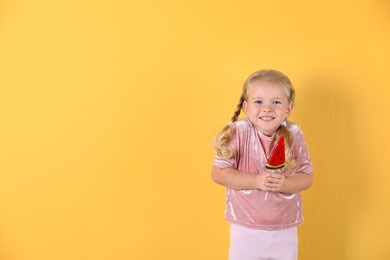 Photo of Cute little girl with candy on color background. Space for text