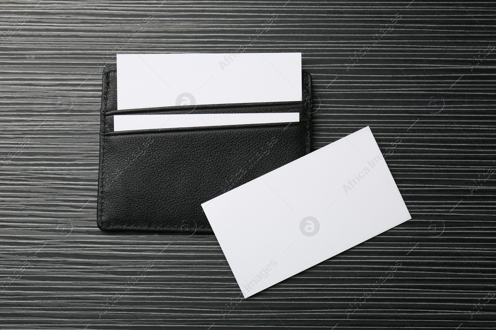 Photo of Leather business card holder with blank cards on grey table, top view