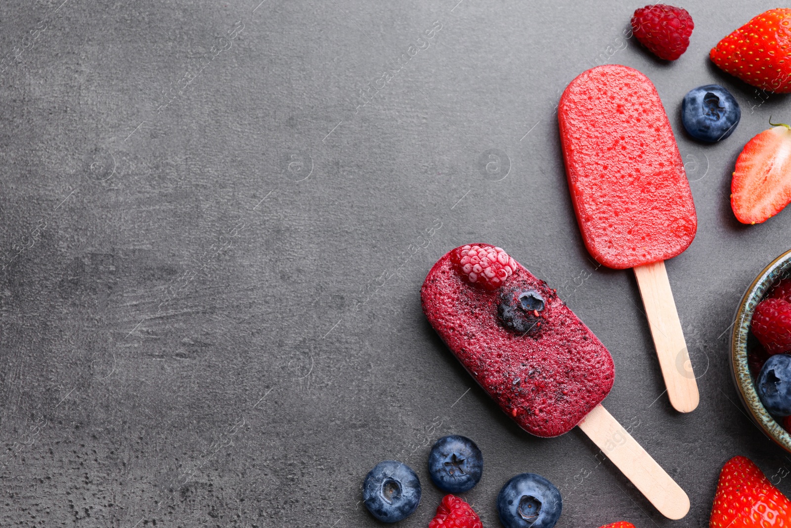 Photo of Tasty fruit ice pops with berries on dark table, flat lay. Space for text