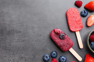 Tasty fruit ice pops with berries on dark table, flat lay. Space for text