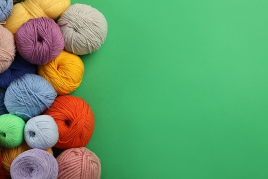Photo of Soft woolen yarns on green background, flat lay. Space for text