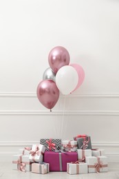 Photo of Many gift boxes and balloons near white wall