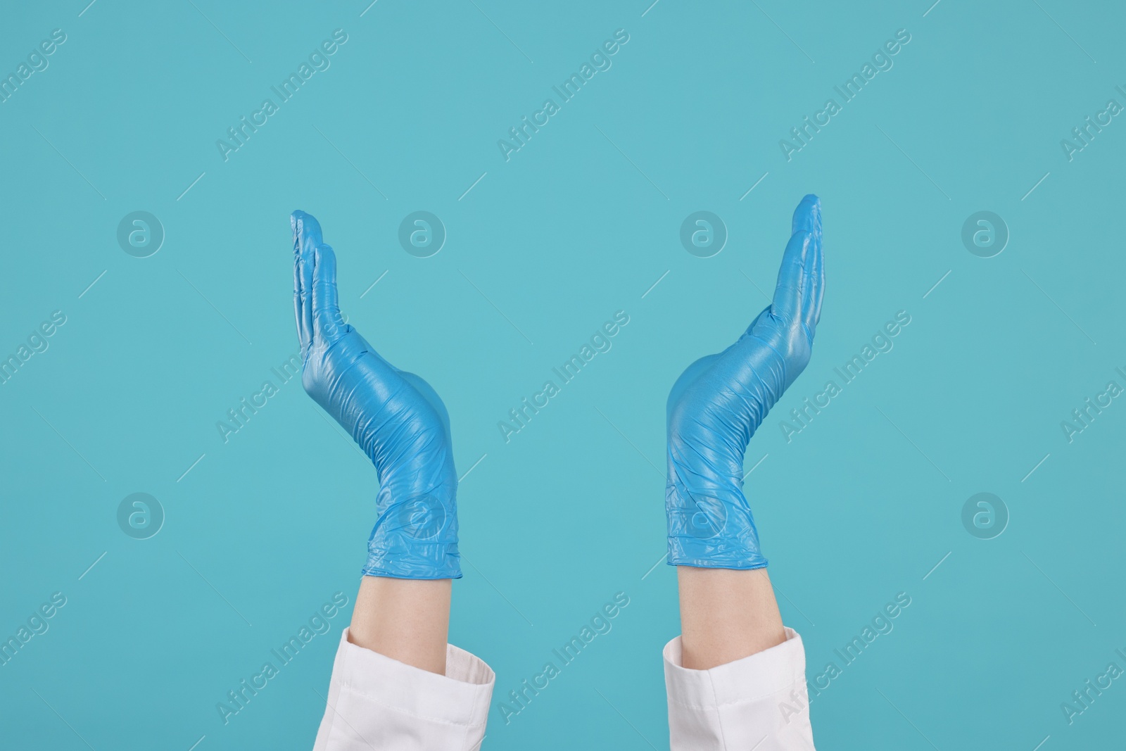 Photo of Doctor holding something on light blue background, closeup