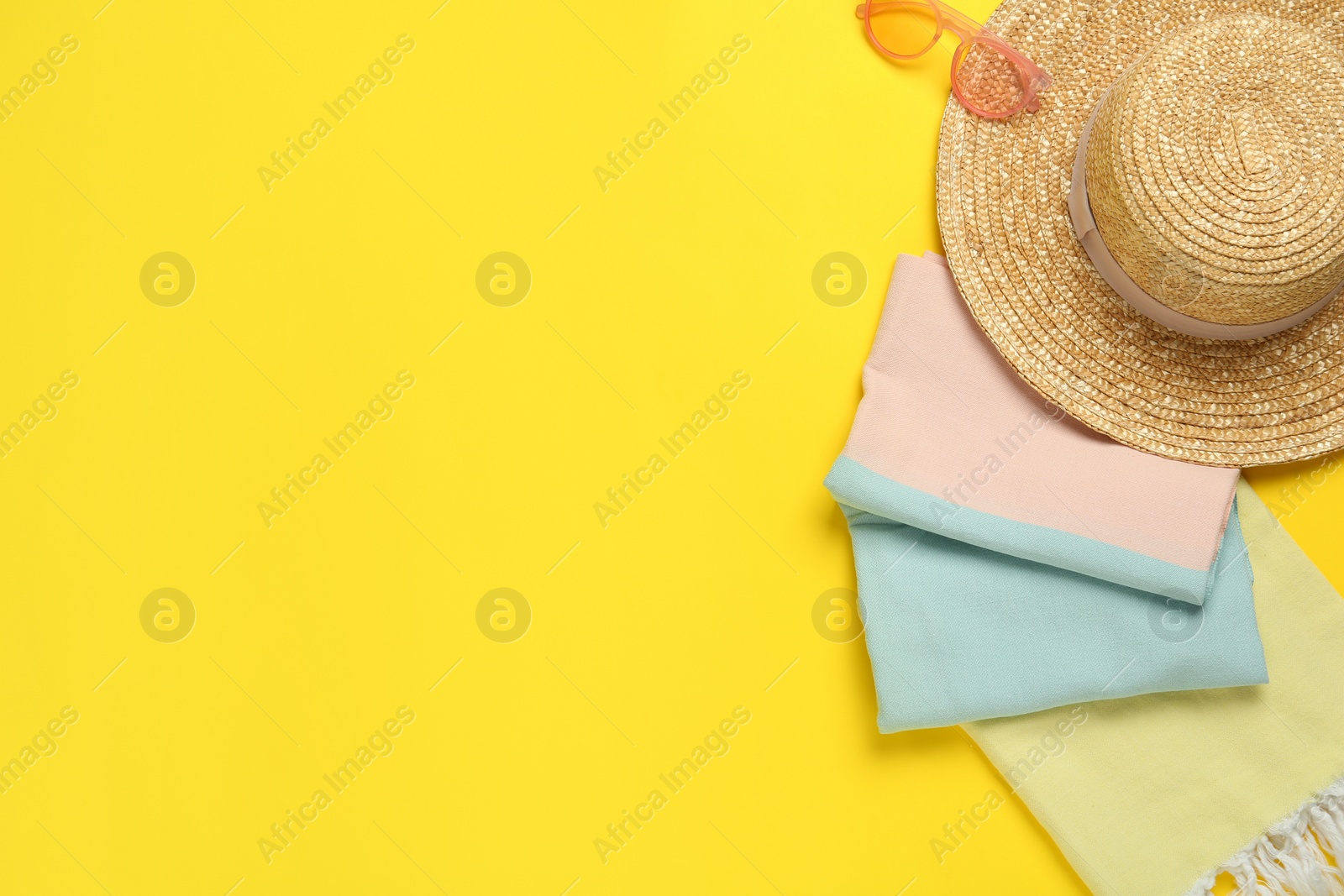 Photo of Beach towel, straw hat and sunglasses on yellow background, flat lay. Space for text