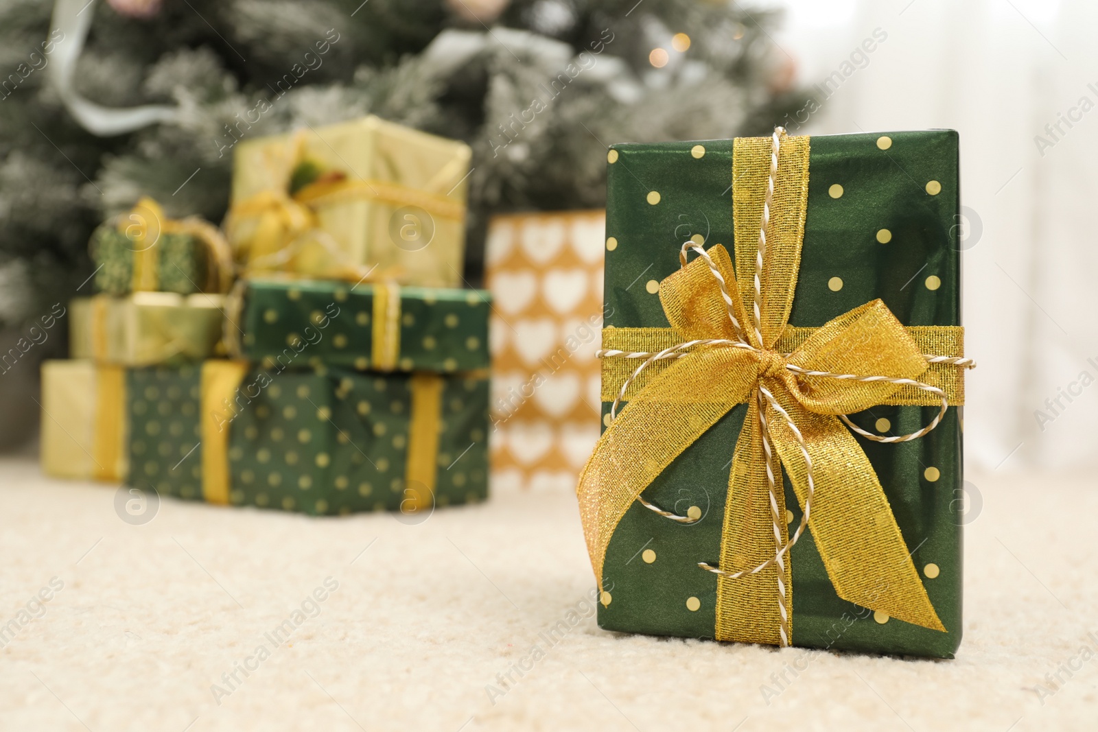 Photo of Beautiful Christmas gift and blurred pile of presents on background. Space for text