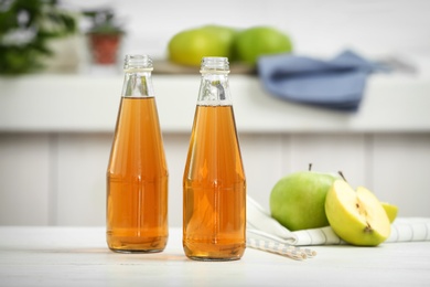 Two bottles of fresh apple juice on table