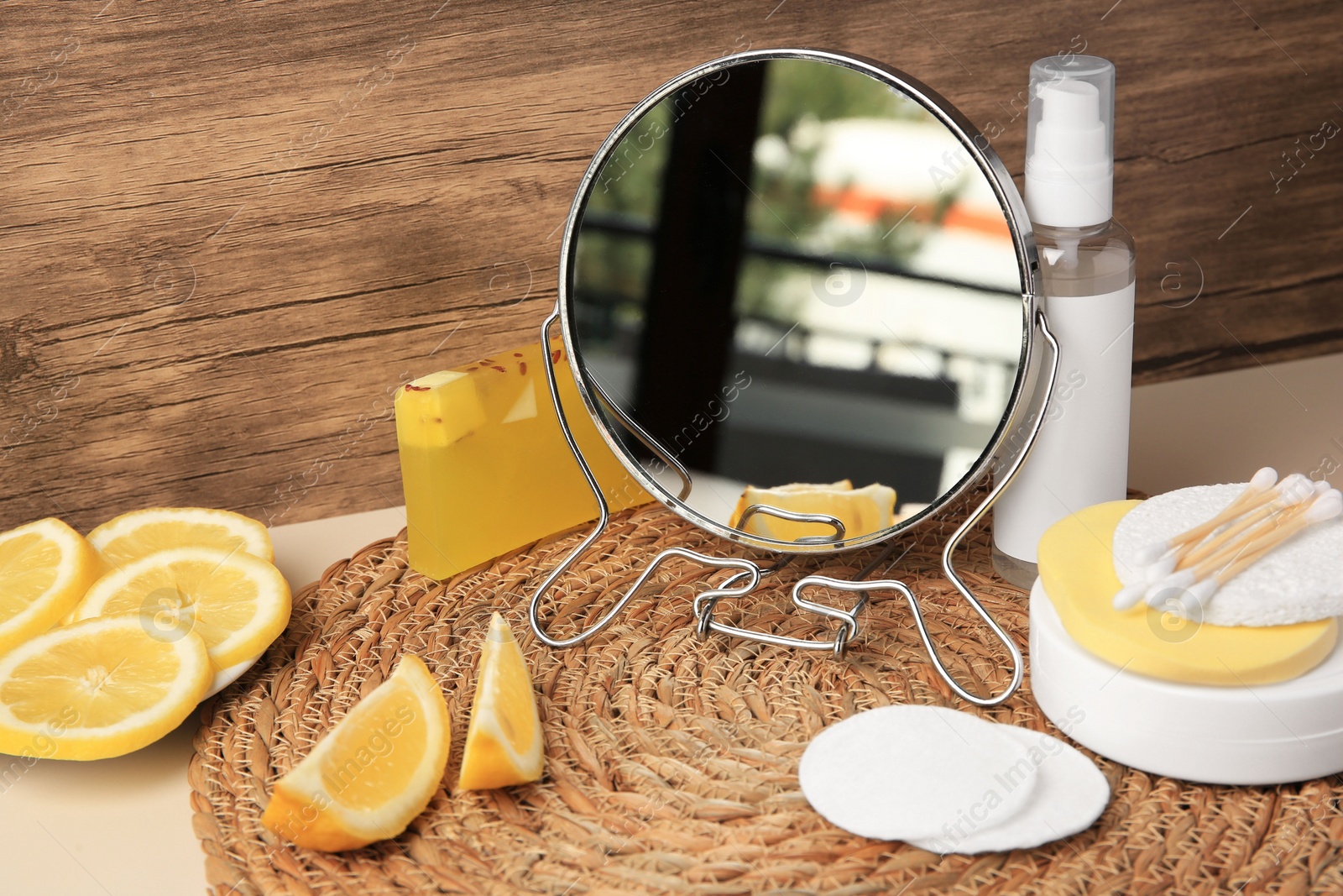 Photo of Lemon face cleanser. Fresh citrus fruits, personal care products and mirror on beige table