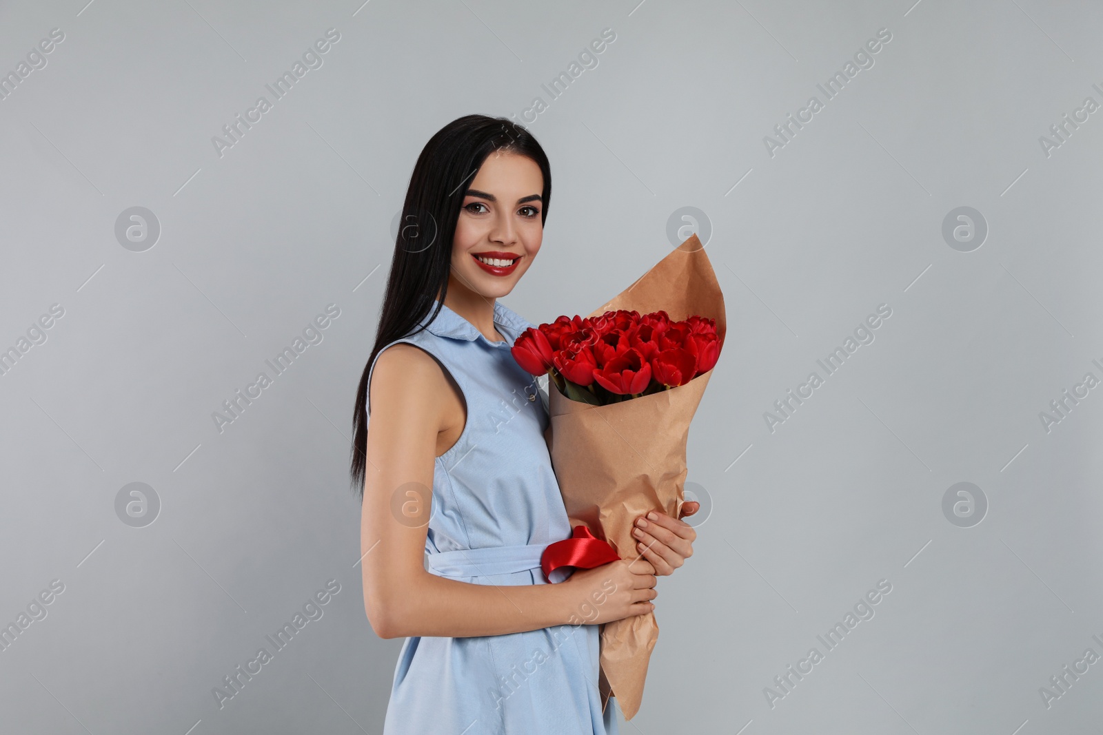 Photo of Happy woman with red tulip bouquet on light grey background. 8th of March celebration