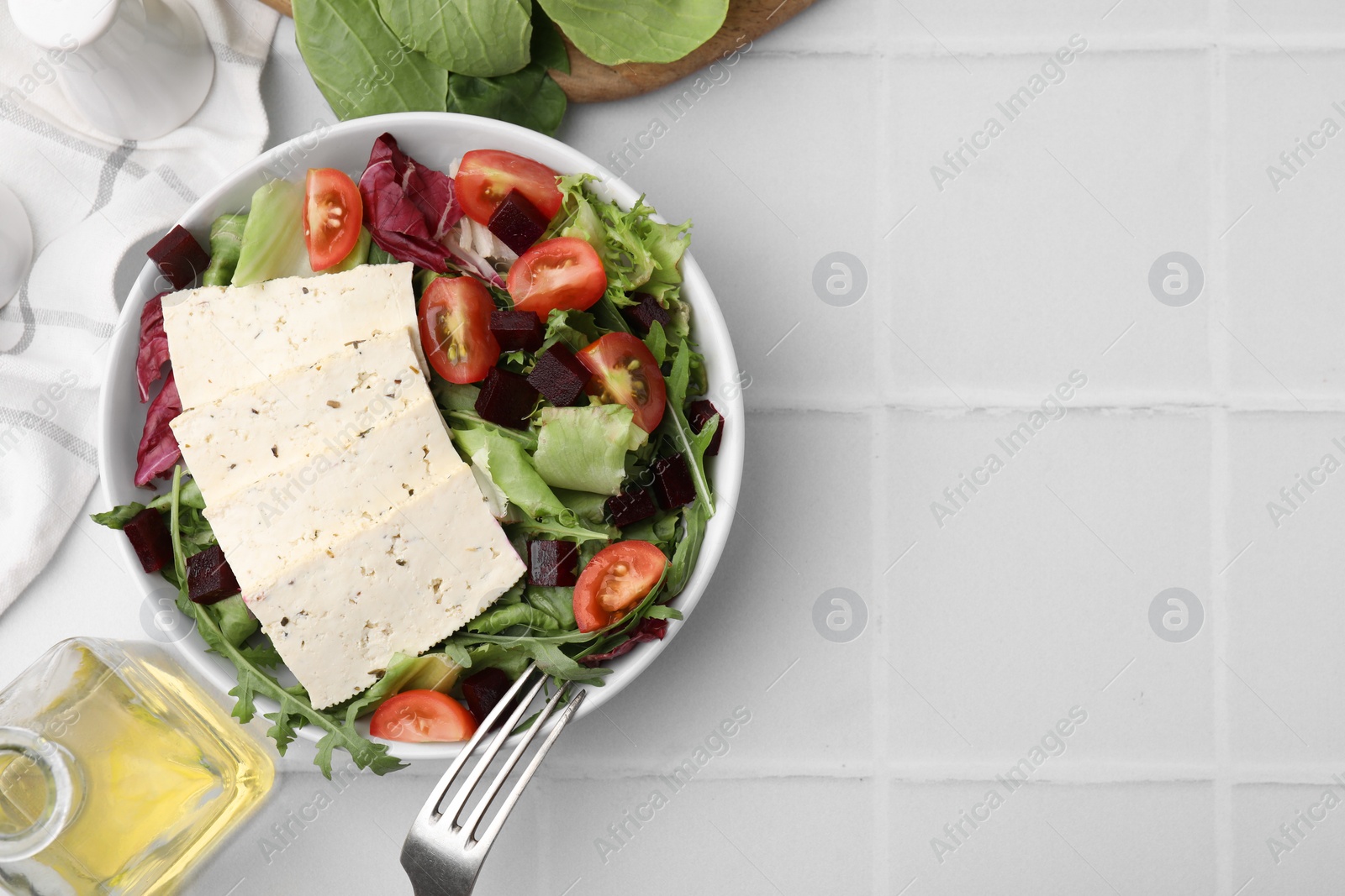 Photo of Tasty salad with tofu and vegetables served on white tiled table, flat lay. Space for text
