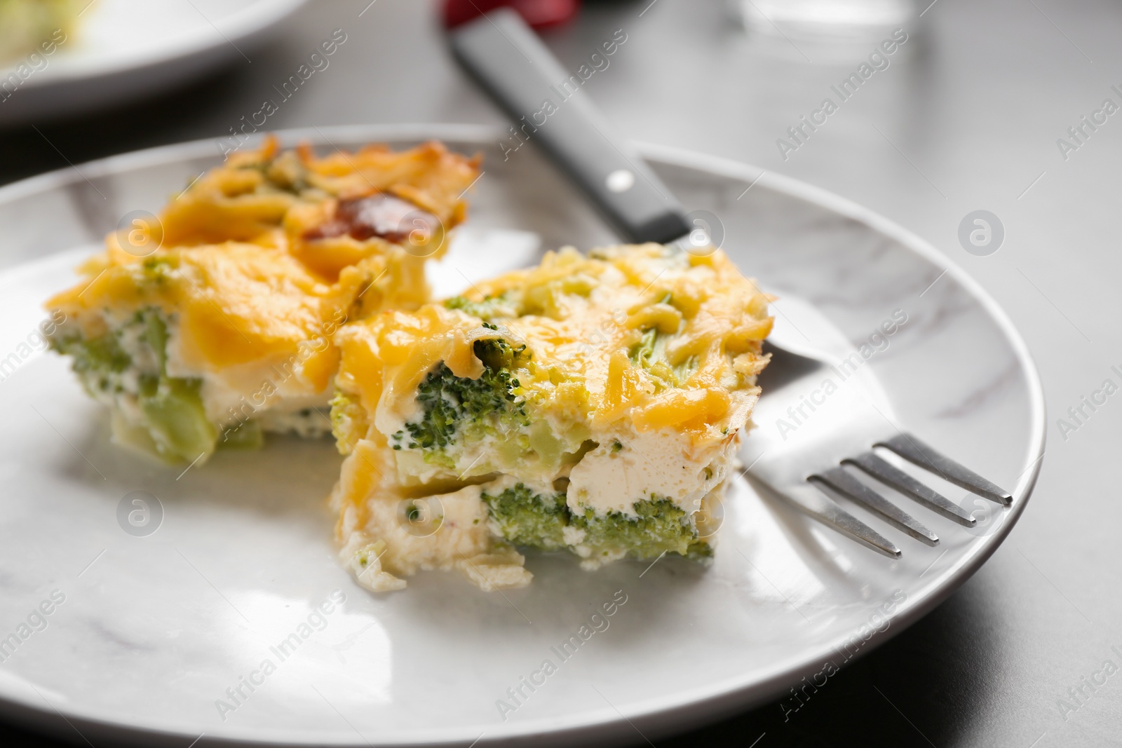 Photo of Pieces of tasty broccoli casserole on grey table