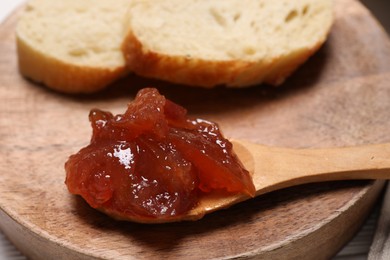 Photo of Delicious apple jam and bread slices on wooden board, closeup