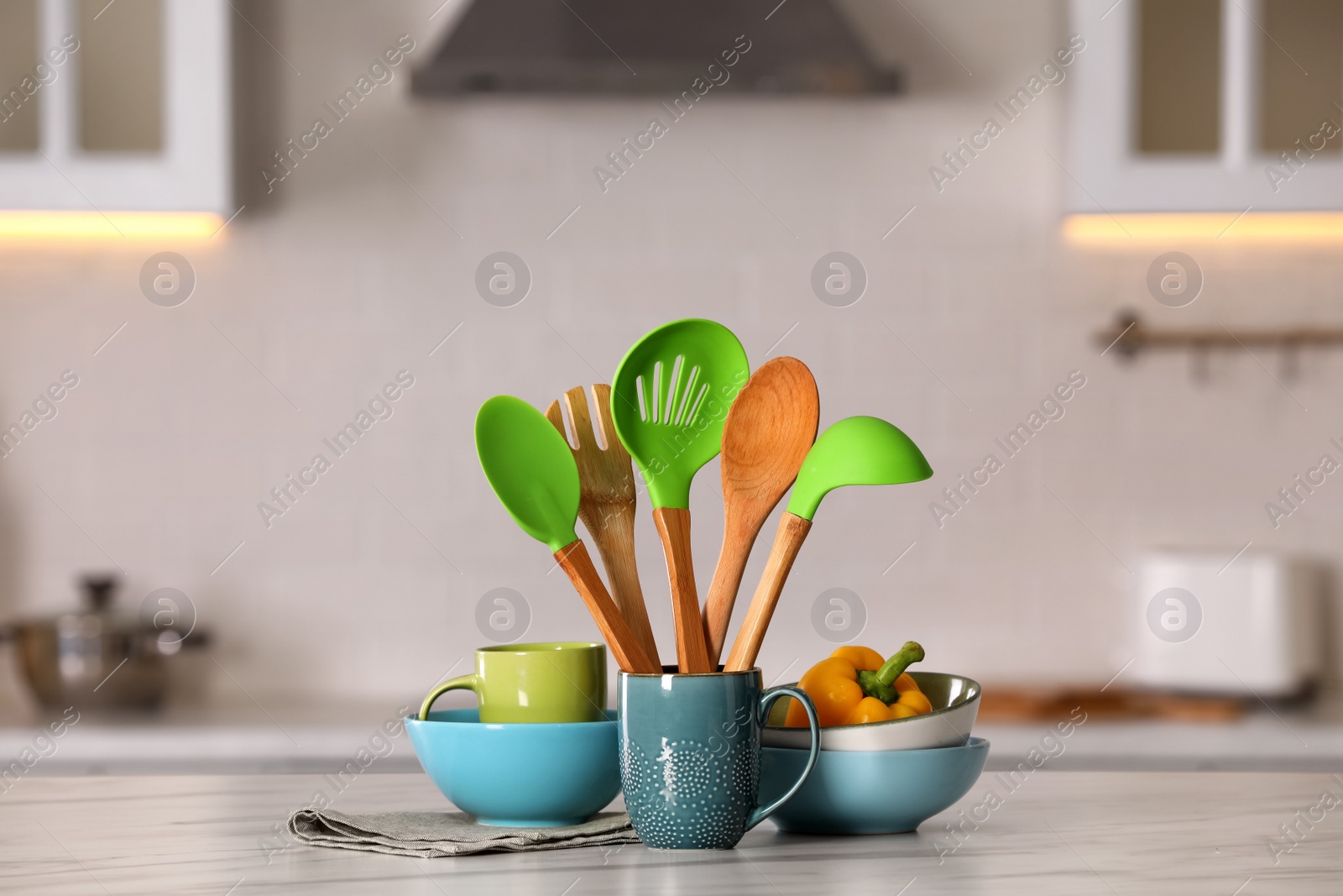 Photo of Set of different cooking utensils and ceramic dishes on white table in kitchen