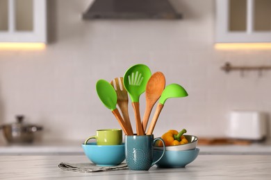 Set of different cooking utensils and ceramic dishes on white table in kitchen