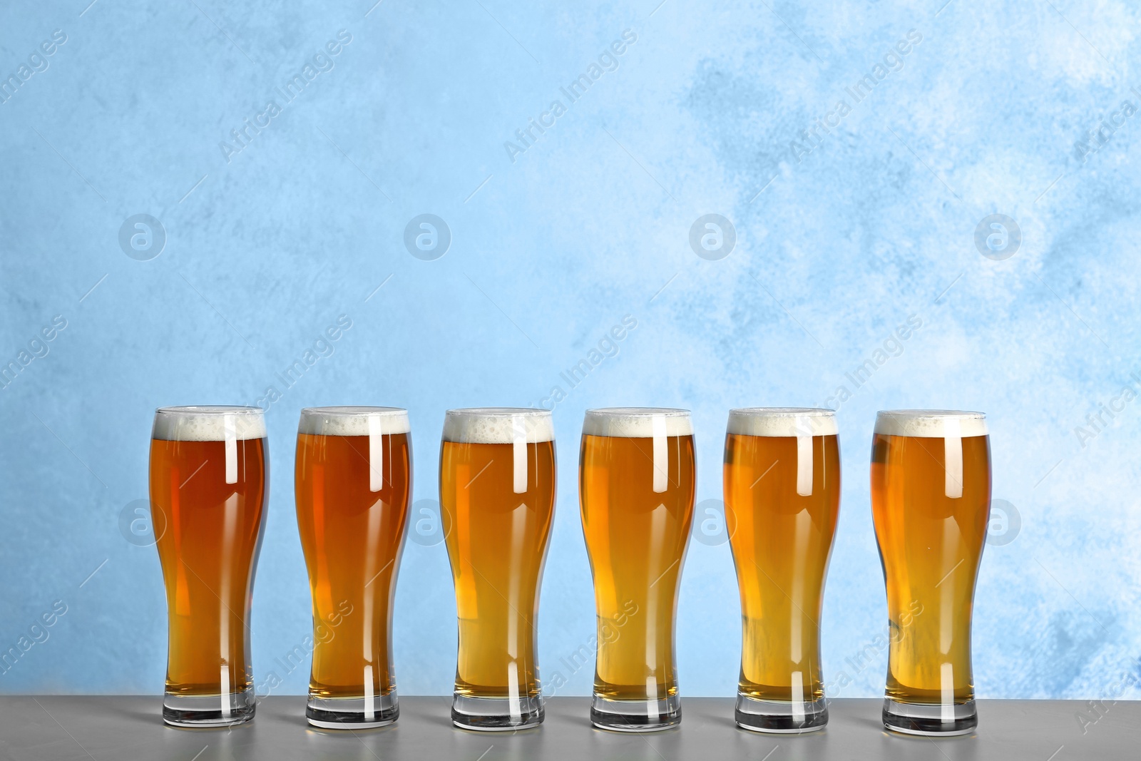 Photo of Glasses with beer on table against color background