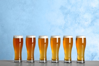 Photo of Glasses with beer on table against color background