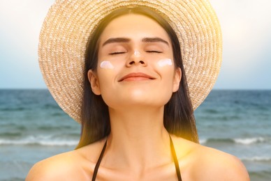 Sun protection. Beautiful young woman with sunblock on her face near sea, closeup