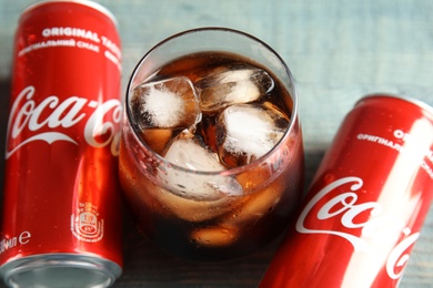 MYKOLAIV, UKRAINE - NOVEMBER 15, 2018: Cans and glass with Coca Cola on table, closeup