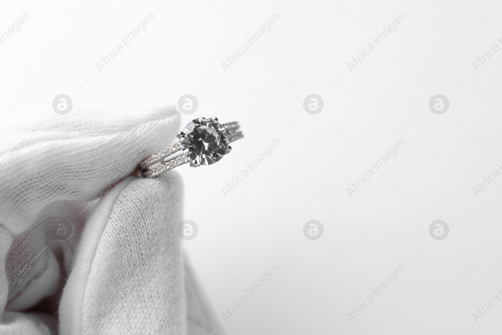 Photo of Jeweler holding diamond ring on white background, closeup. Space for text