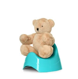 Teddy bear sitting on blue potty against white background. Toilet training