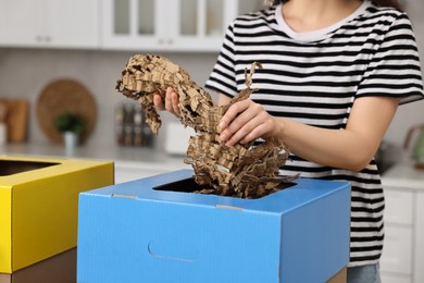 Garbage sorting. Woman throwing shredded paper into cardboard box in kitchen, closeup