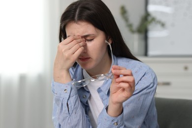 Overwhelmed woman with glasses suffering from headache at home