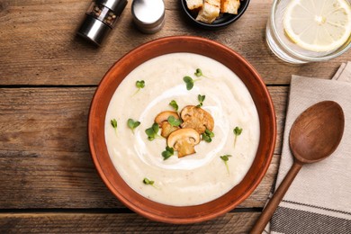 Photo of Delicious cream soup with mushrooms served on wooden table, flat lay