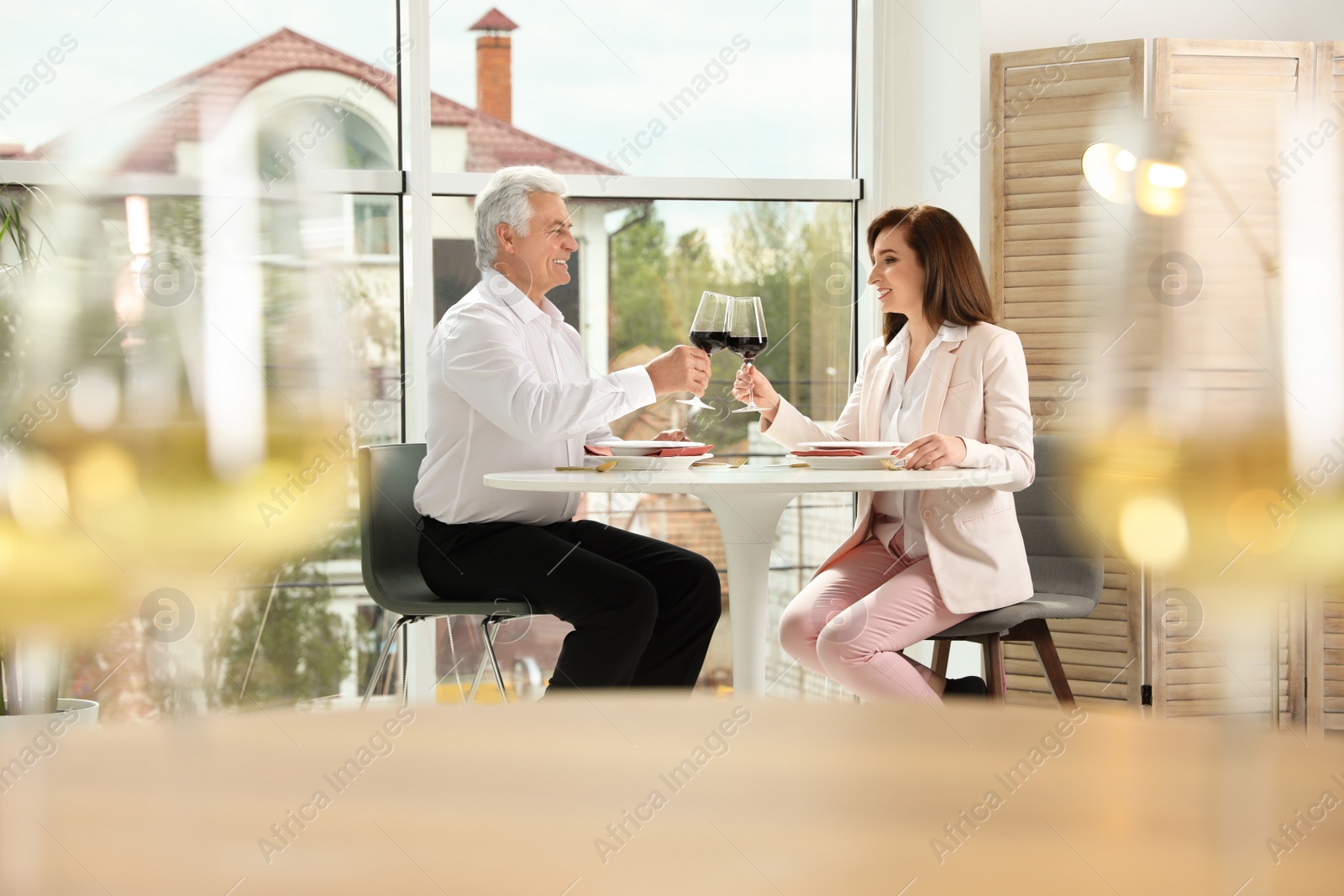 Photo of Man and woman with glasses of wine at table in restaurant