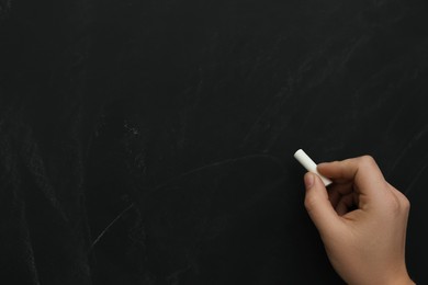 Man with white chalk near blackboard, closeup. Space for text