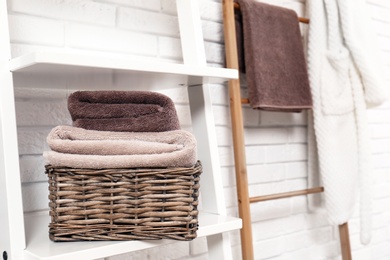 Photo of Basket with clean towels on shelf near brick wall. Space for text