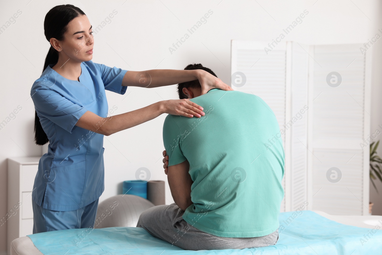 Photo of Orthopedist examining man's neck in clinic. Scoliosis treatment