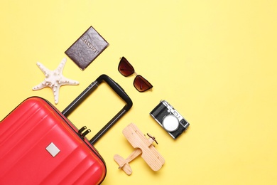 Photo of Flat lay composition with suitcase and beach objects on yellow background. Space for text