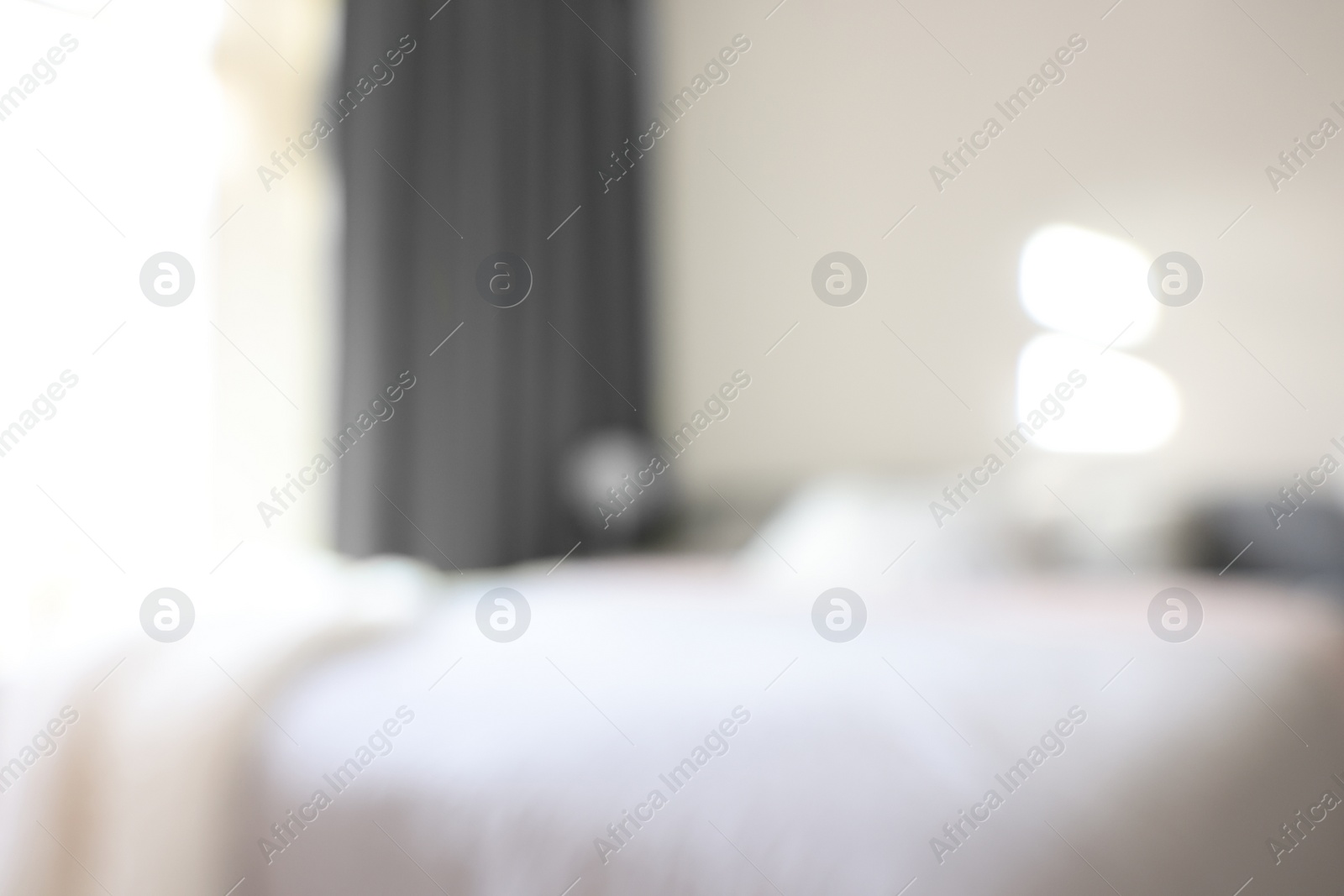 Photo of Blurred view of large bed near window in room