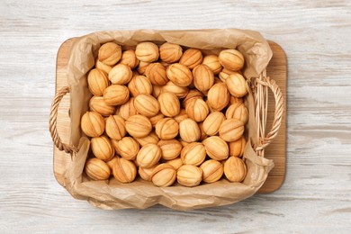 Wicker basket of delicious nut shaped cookies with boiled condensed milk on light wooden table, top view