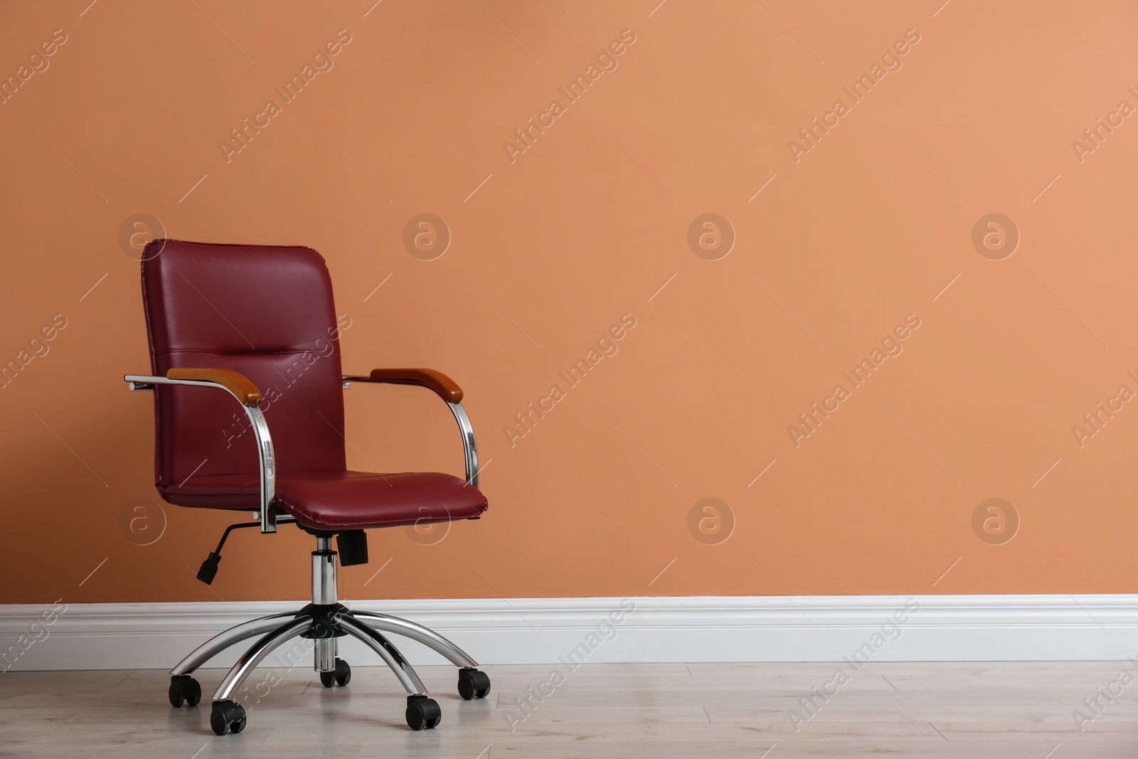 Photo of Modern office chair near orange coral wall indoors. Space for text