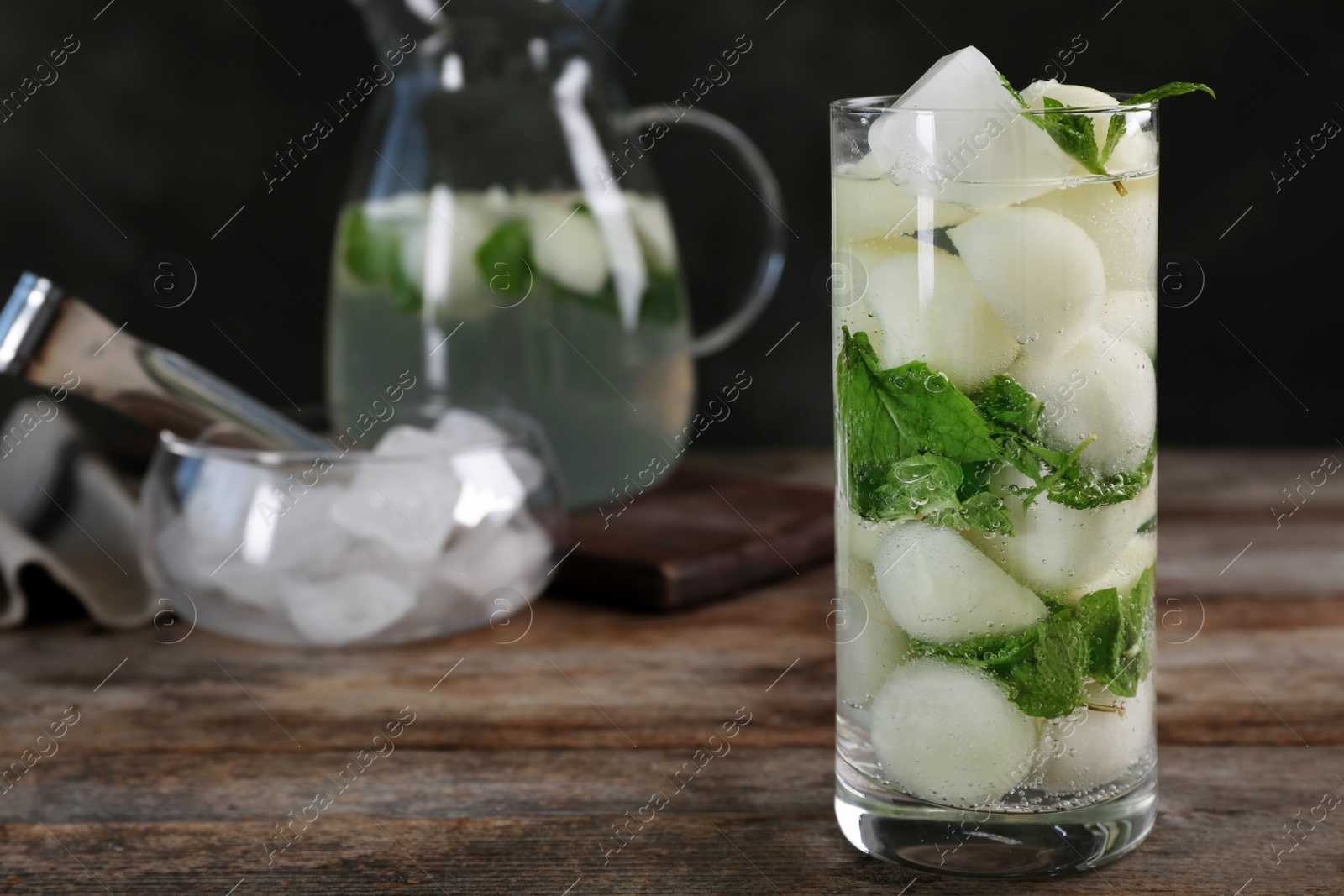 Photo of Glass with tasty melon ball drink on wooden table