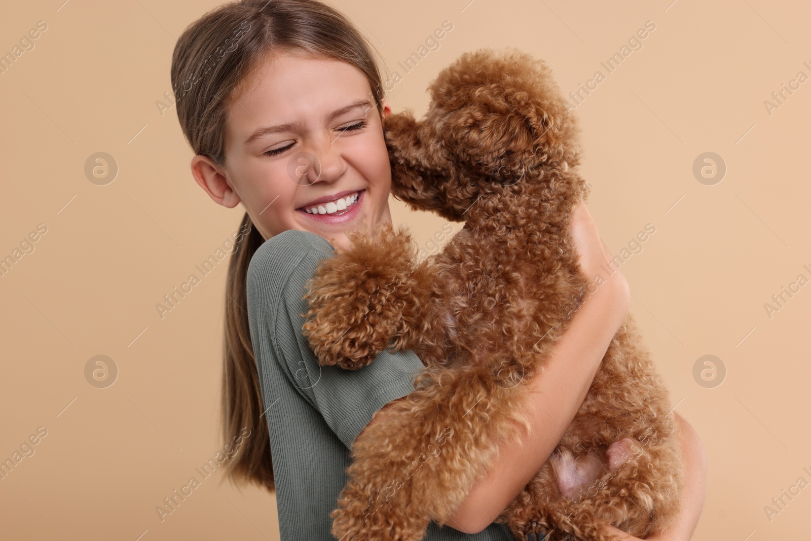 Photo of Little child with cute puppy on beige background. Lovely pet