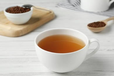 Cup of buckwheat tea on white wooden table