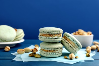 Delicious macarons and pistachios on blue wooden table