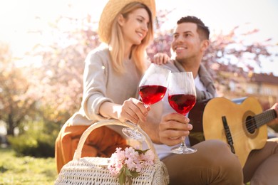 Photo of Lovely couple having picnic in park, focus on hands with glasses of wine
