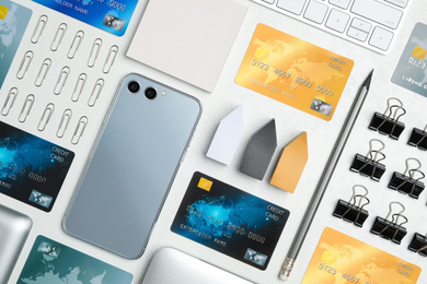Flat lay composition with credit cards, smartphone and stationery on white table