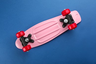 Photo of Pink skateboard on blue background, top view