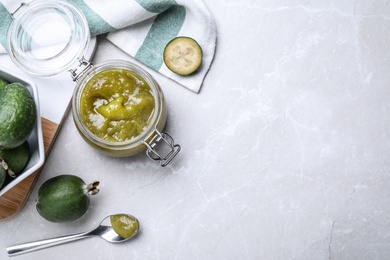 Photo of Feijoa jam and fresh fruits on light grey table, flat lay. Space for text