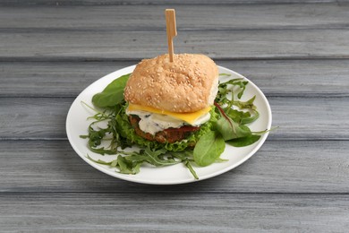 Photo of Delicious vegetarian burger served on grey wooden table