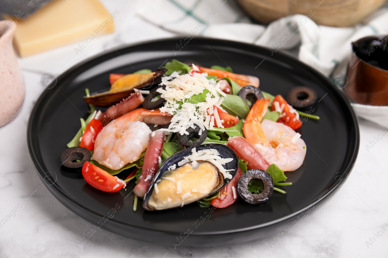 Photo of Plate of delicious salad with seafood on white marble table, closeup