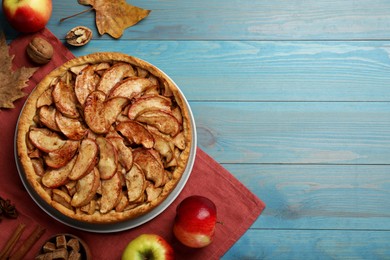 Photo of Delicious apple pie and ingredients on turquoise wooden table, flat lay. Space for text